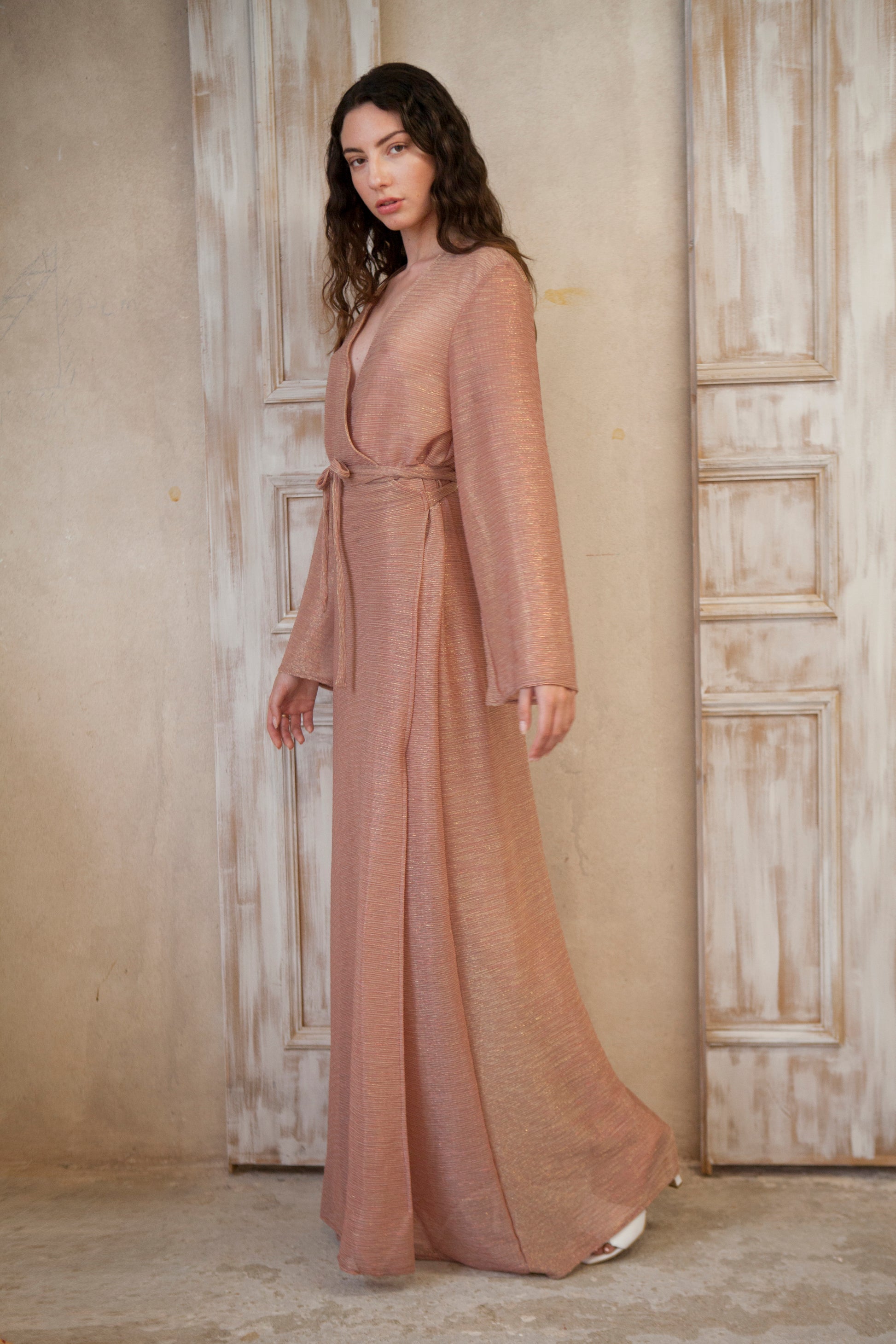 Long-sleeved, maxi-length wrap designed dress. Crafted from glinting fabric
