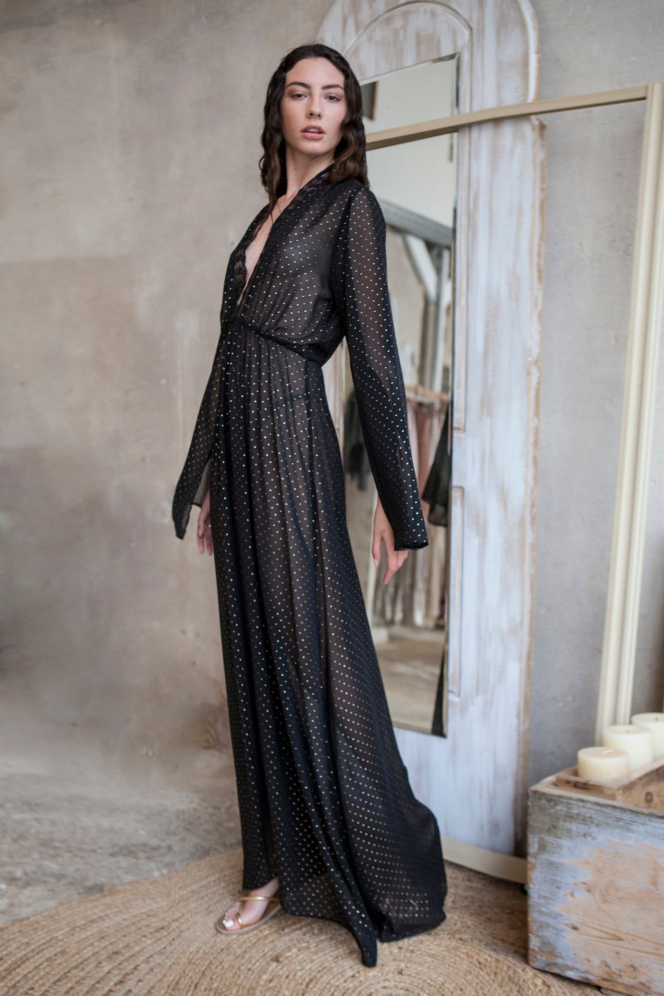 Black maxi dress, featuring a deep V neckline trimmed with delicate lace and a sultry front slit. Crafted from 3D small gold dots fabric
